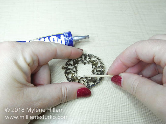 Using a toothpick to apply the adhesive to the fine detail of the filigree
