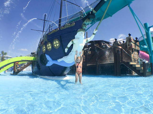 Little girl standing in front of color ship in waterpark