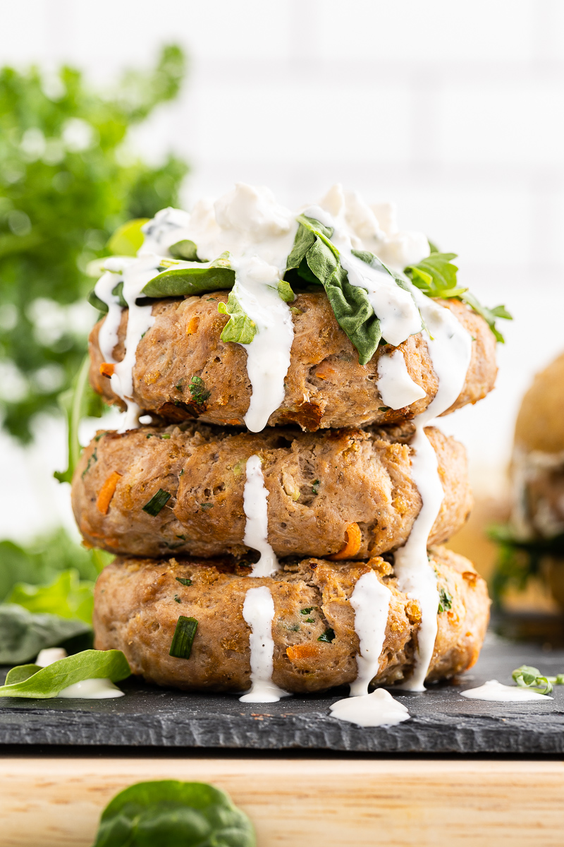 Stack of three Keto Buffalo Chicken burger patties with blue cheese sauce on them.