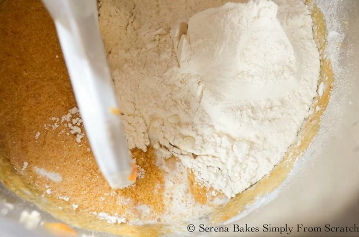 Flour added to Peach Upside Down Cake batter in a stainless steel mixing bowl.