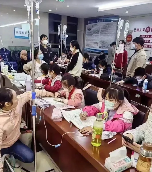 Young Chinese kids in China doing homework at hospital while hooked up to IV fluid drips