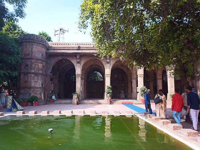 Pool of water in front of Sidi Saiyyeh Mosque with visitors removing their shoes outside