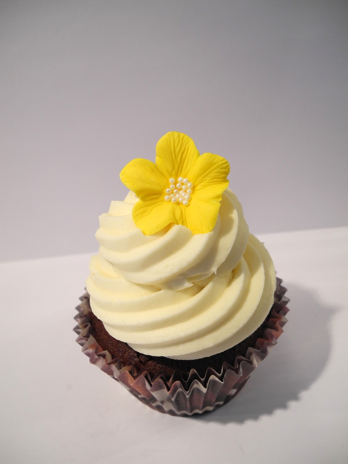 chocolate cupcakes white frosting en gul blomma att toppa frostingen med och pa tal om frostingen sa 