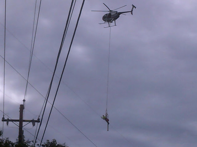 A telephone line worker hanging from a helicopter checking the wires