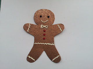 Gingerbread man shape embossed in copper and decorated with white paste and gems