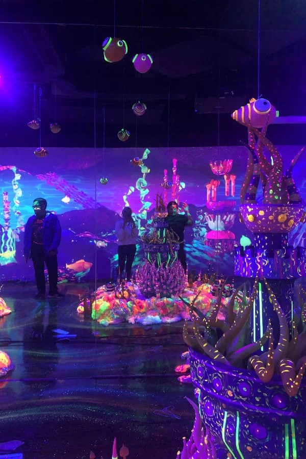 standing visitors look at vivid rolled paper fantasy undersea exhibit