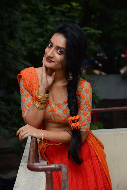 Janani Reddy in orange traditional wear, showcasing a cute navel.