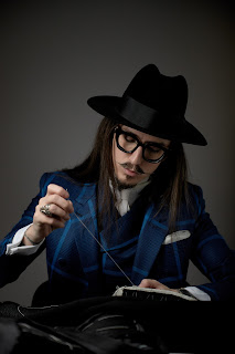 Tailor Joshua Kane in an elegant suit posing with needle and thread