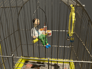 clay figure sitting in bird cage