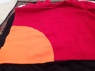 A large quarter-circle of bright-orange fabric set on screaming red fabric.