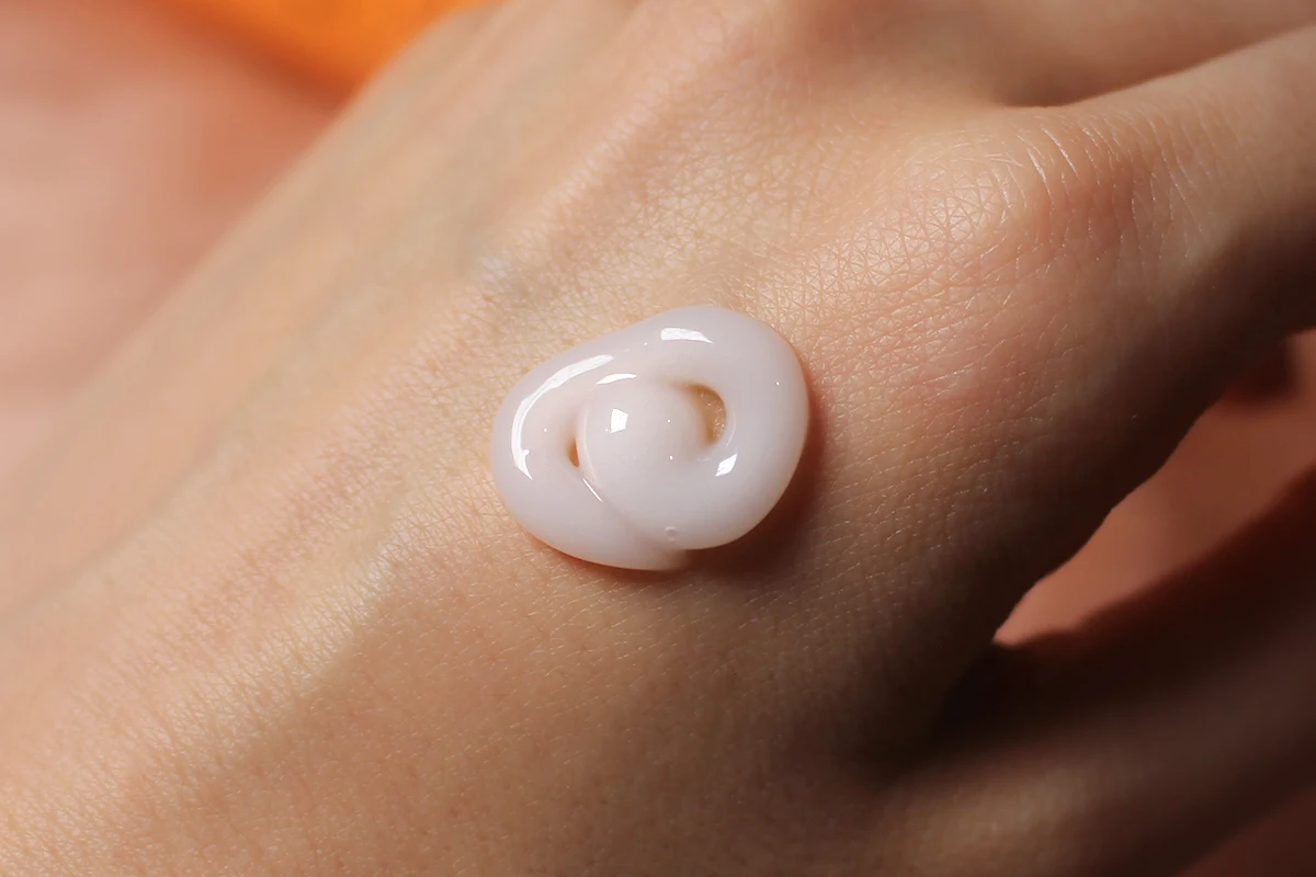 a close-up swatch of a Elizavecca Cer-100 Collagen Coating Hair Curl Cream on a woman's hand