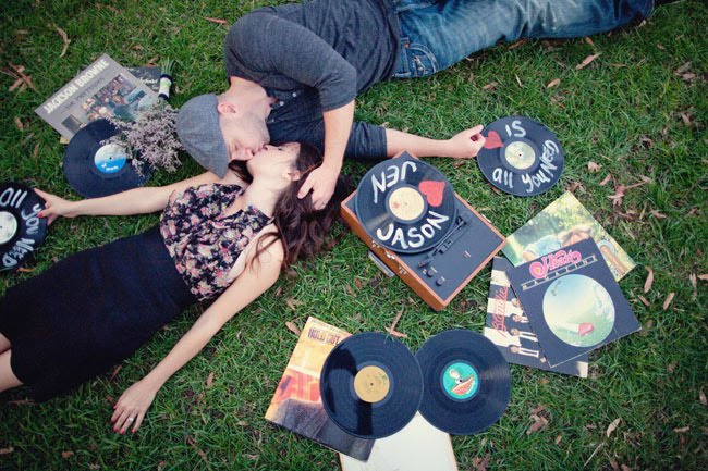 couple kissing with records on grass record player