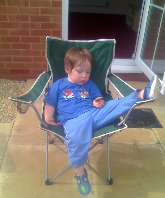 Toddler Sleeping Slumped in a Lawn Chair. Clutching a Cookie