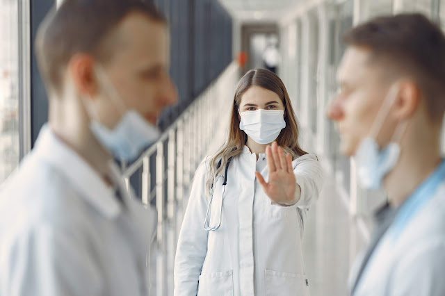 People in white uniforms wearing medical masks.