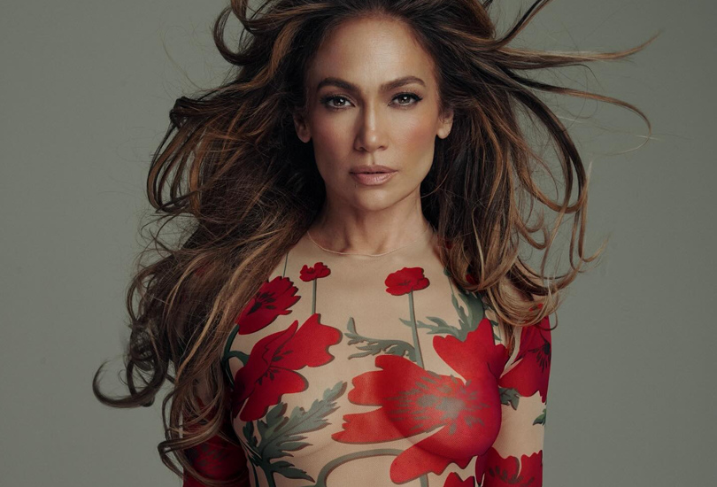 A shot from the photoshoot for Jennifer Lopez’s album ‘This Is Me...Now’. Jennifer is wearing a flesh coloured bodysuit with red flowers on it, as she looks into the camera. Photographed by Norman Jean Roy.