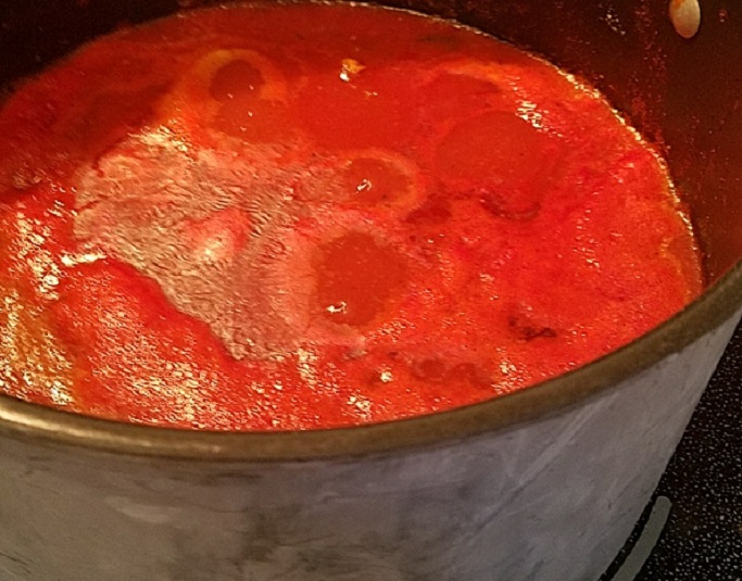 plum ripe tomatoes to make homemade Italian sauce is in this black pot