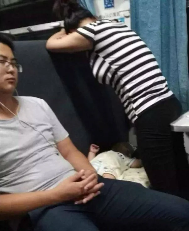 Mother in train covering her child with her body for a good sleep