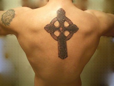 Black cross tattoo on man's upper arm and unique cross tattoo on white