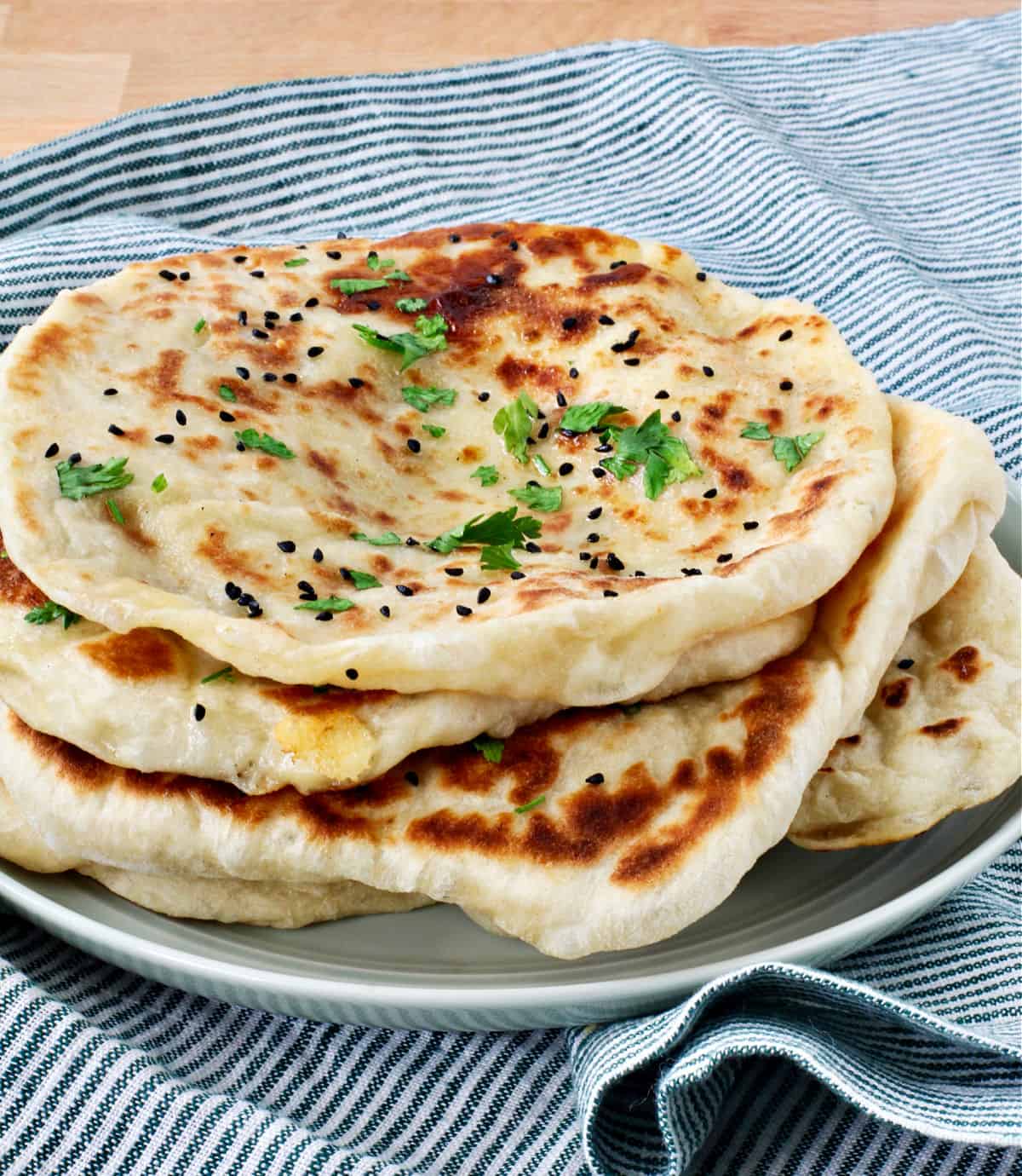 Garlic and Cheese Naan stacked on a green plate.