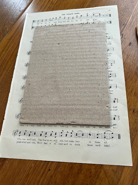 Photo of tracing a cardboard frame insert on a songbook page.