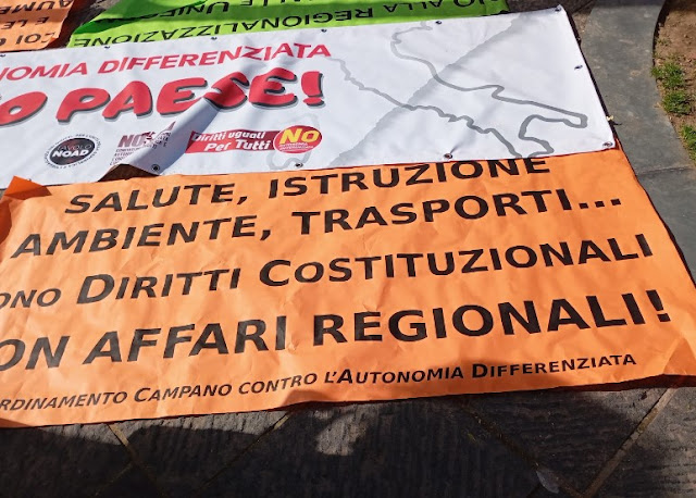 Cartello che recita: Salute, istruzione, ambiente, trasporti... Sono diritti costituzionali, non affari regionali