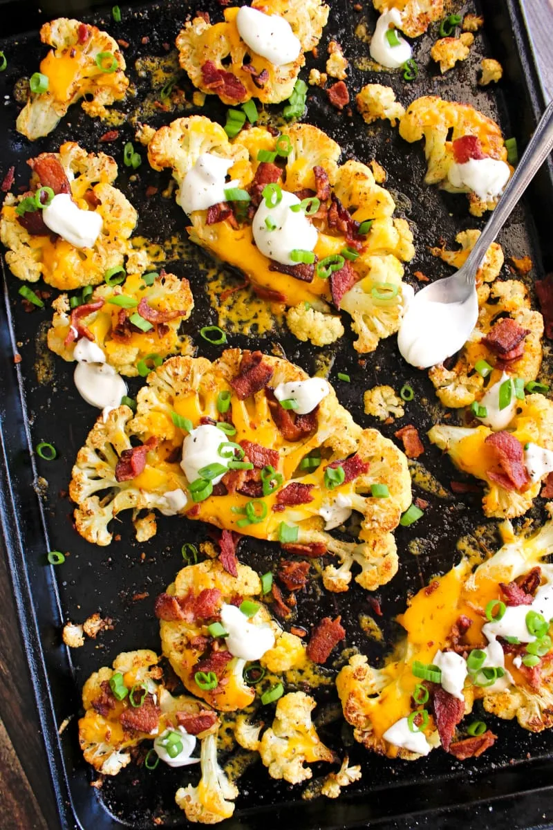 Top view of loaded cauliflower steaks on a sheetpan.