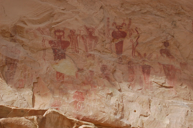 Many red pictographs of alien-like people on a white rock wall in 9 Mile Canyon Utah