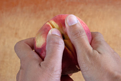 Gently twisting two halves of a peach apart