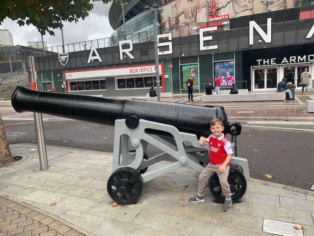 Boy standing next to a canon, outside the Emirates stadium, home to Arsenal Football Club