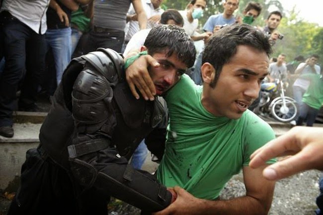 35 moments of violence that brought out incredible human compassion - an iranian police officers is protected by cilicians after being beaten by rioters