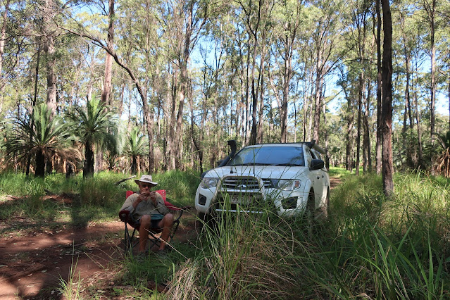 John sitting in camp chair eating lunch in front of his car on the road