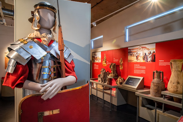 Part of the Roman displays in Castleford Museum, with a mannequin in replica Roman centurion armour in the forefront and a series of Roman statues and amphorae in the background.