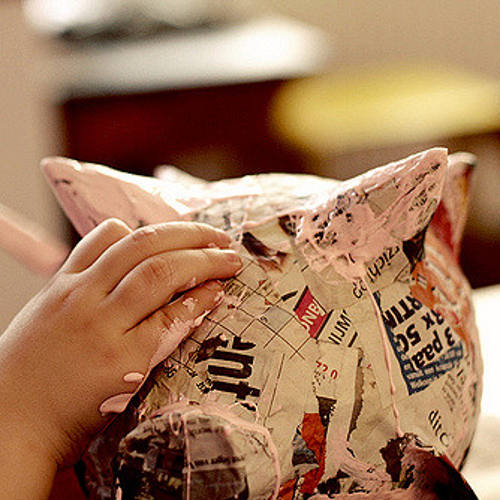 newsprint newspaper covered paper mache pig being painted pink