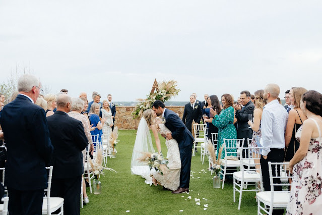 bride and groom kissing in the middle of the aisle with guests clapping