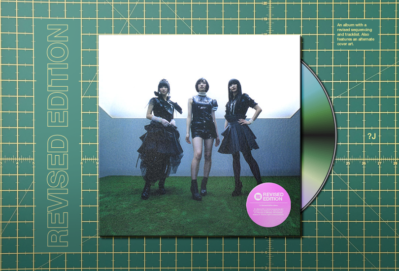 A post header, featuring the text ‘REVISED EDITION’ set vertically / rotated counterclockwise beside a CD slip cover on a green cutting mat. The slip cover is for a revised edition of Perfume’s Game—the cover of which features Perfume [from left to right: a-chan, Nocchi and Kashiyuka] stood wearing Goth Lolita style outfits in a silver room with a grass floor and a lightbox ceiling.