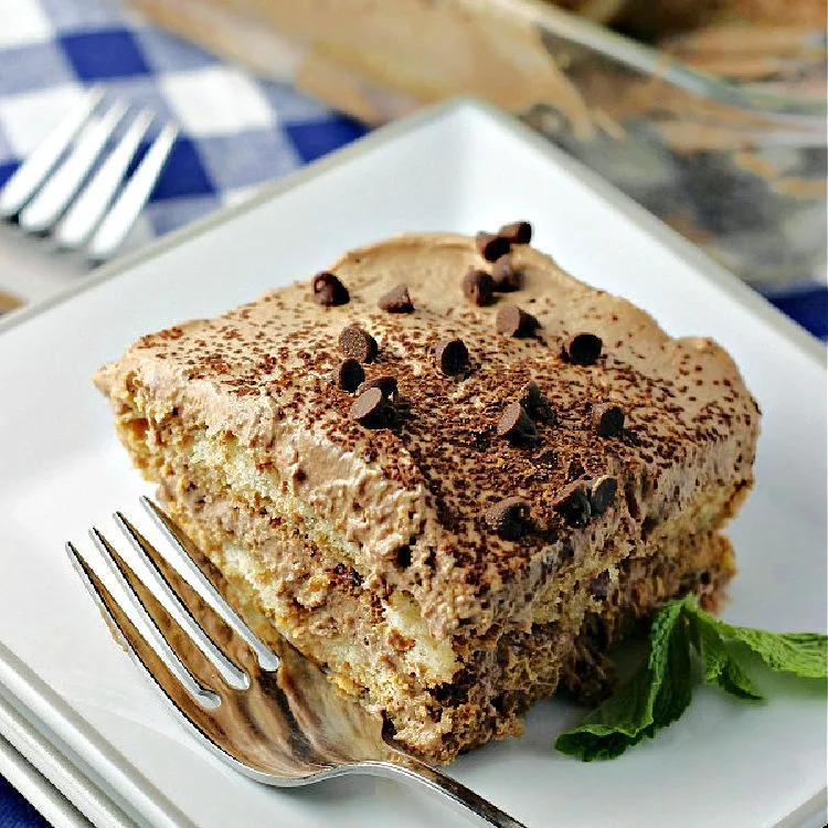 A piece of chocolate tiramisu on a white plate with a fork ready to eat