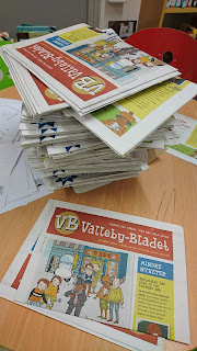 Bord där det ligger en stor hög Vallebybladet plus några enstaka ex bredvid. På framsidan finns Lasse, Maja och flera andra figurer ur böckerna.