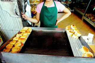 A female vendor holds up a pair of tongs as she awaits order for hopia to be reheated and sold