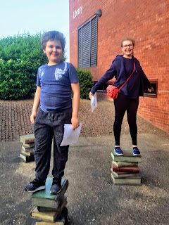 Top Ender and Dan Jon standing on piles of books