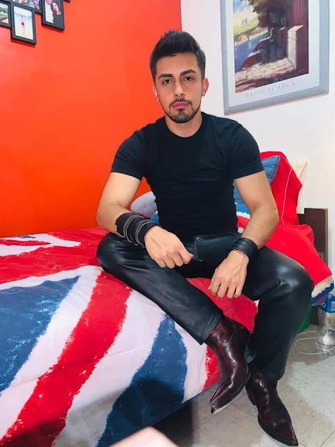 9/11 handsome tan skins stud wearing black leather pants a t-shirts tucked in and cherry red cowboy boots and he sits on his bed showing off inviting somebody to come spend time with him