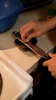 Image of two hands working a nutmeg seed over a micro-planer.  