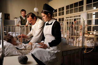 A nurse (Henriette Confurius) hands a drink to a boy in a hospital bed. Courtesy of StudioCanal.