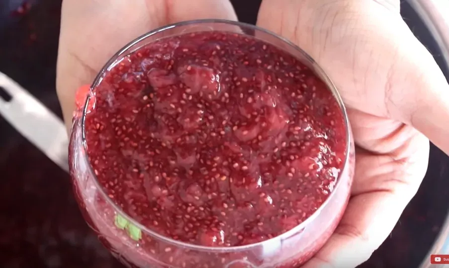 Hands holding a cup of strawberry jam, red color