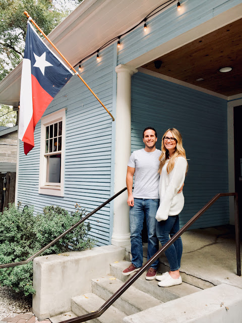 couple smiling on front porch with texas flag flying