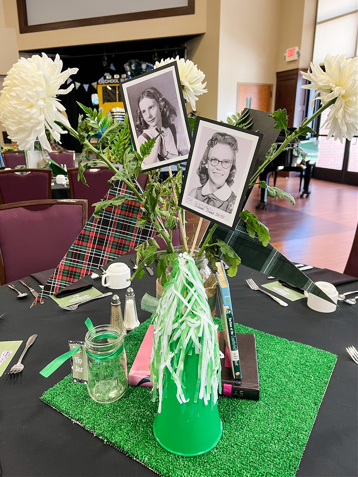 School Days Centerpiece with green turf square base, books, pennants, and vintage school photos in flower vase