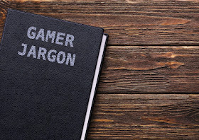 A book, bound in black textured leather, entitled 'Gamer Jargon,' on a wooden surface.