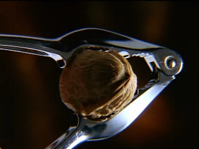 Slow motion close up walnut being cracked by nutcracker