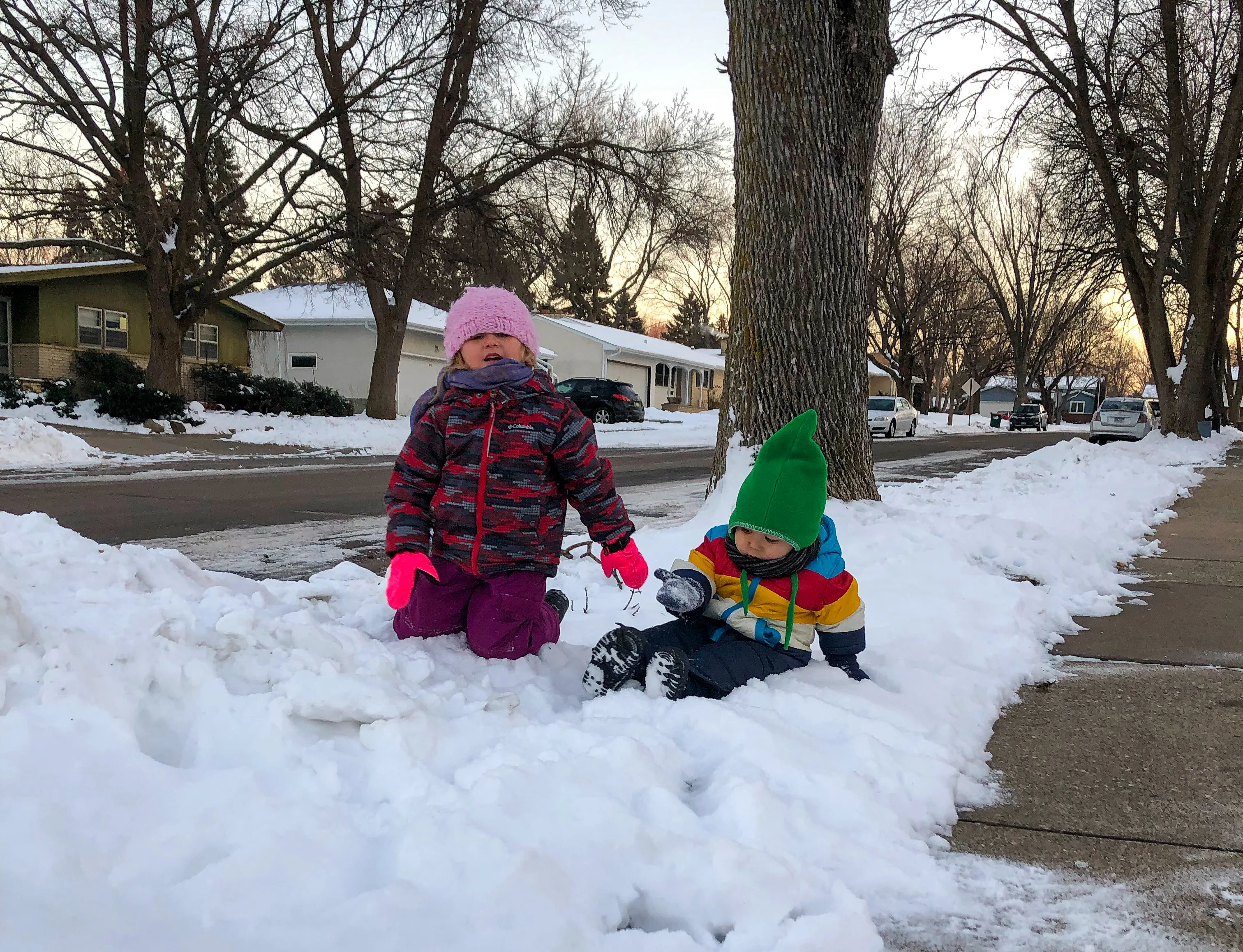 A Montessori toddler and preschooler are playing in the snow during the winter.