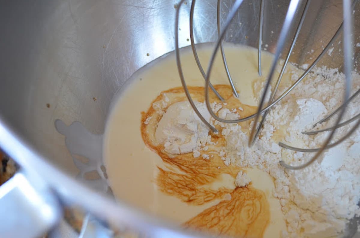 Heavy Whipping Cream, Vanilla Extract, and Powdered Sugar in a stainless steel mixing bowl with mixer fitted whisk attachment.