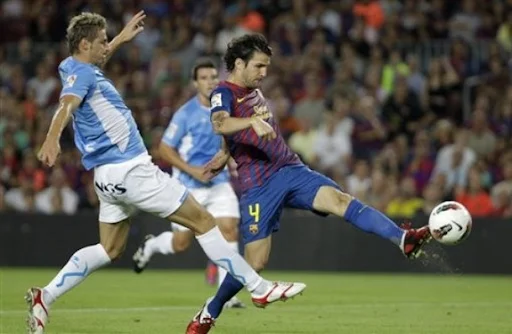Cesc Fàbregas shoots to score against Osasuna after exchanging passes with Lionel Messi